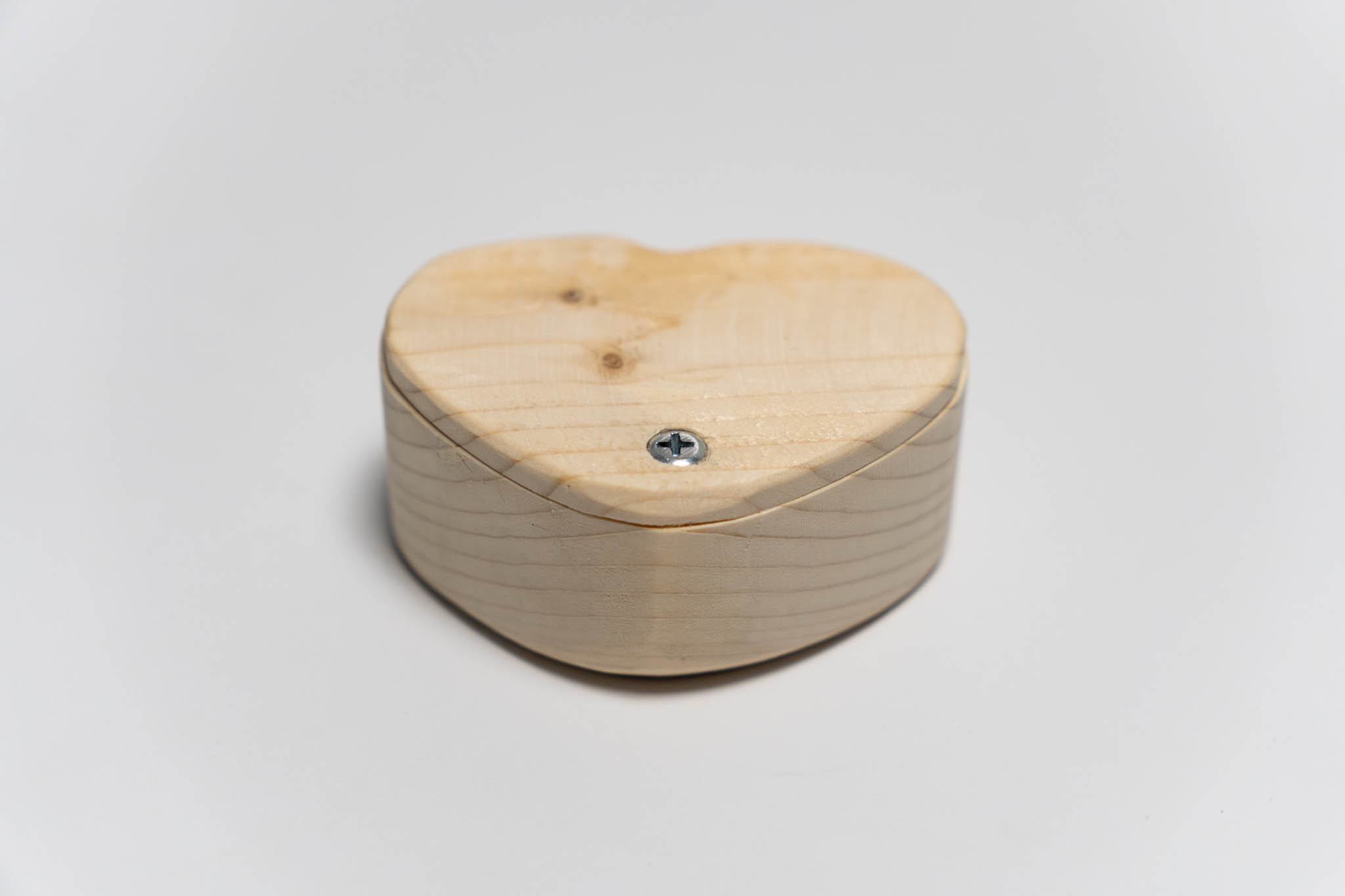 a small heart-shaped wooden beige box with its lid ancored around the tip, closed