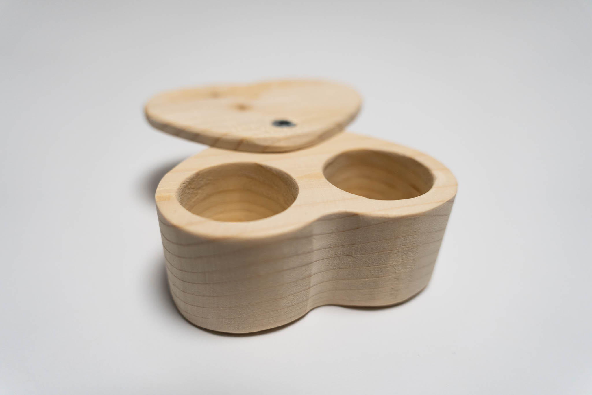 a small heart-shaped wooden beige box with its lid ancored around the tip, fully open