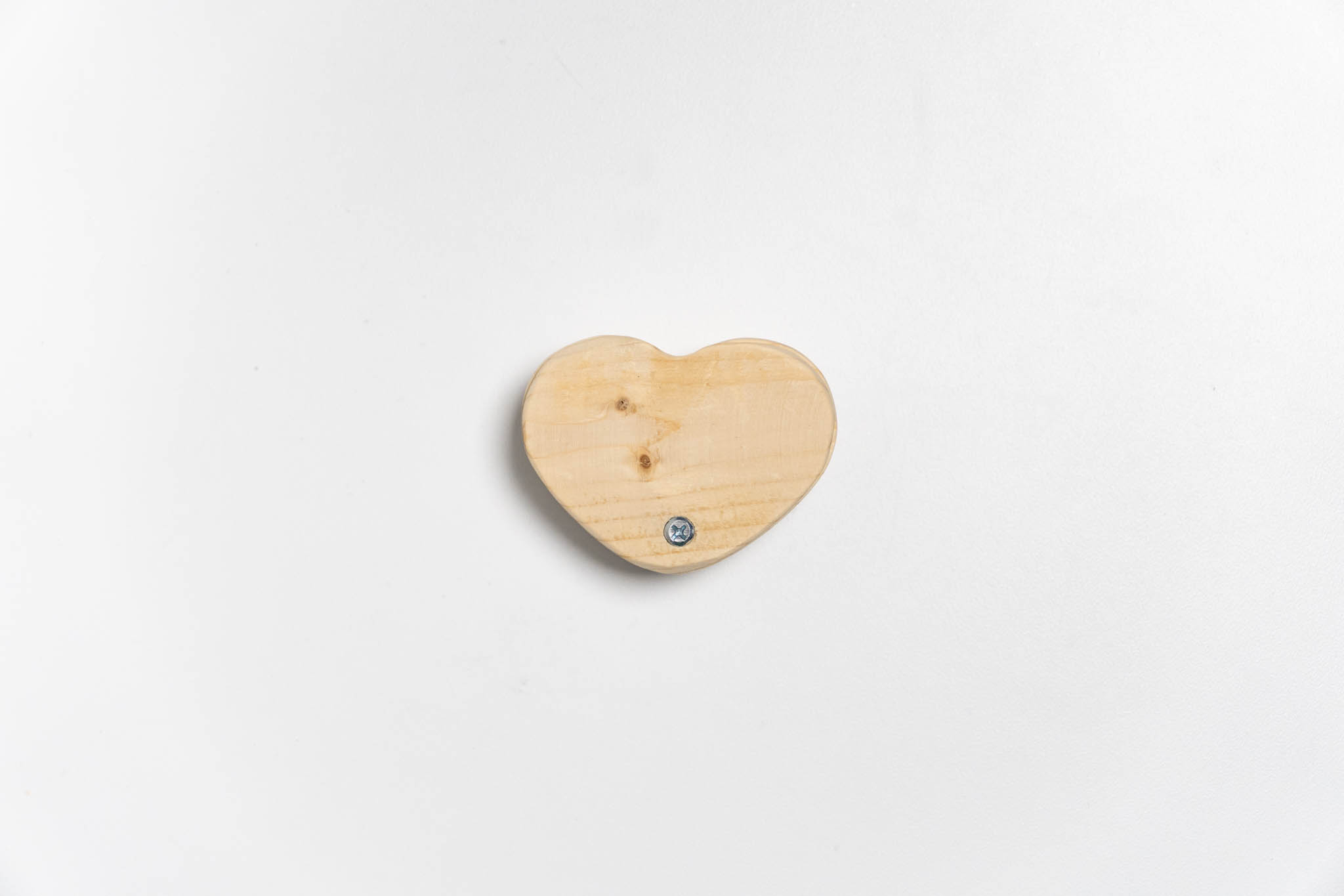 top view of a small heart-shaped wooden beige box with its lid ancored around the tip, closed