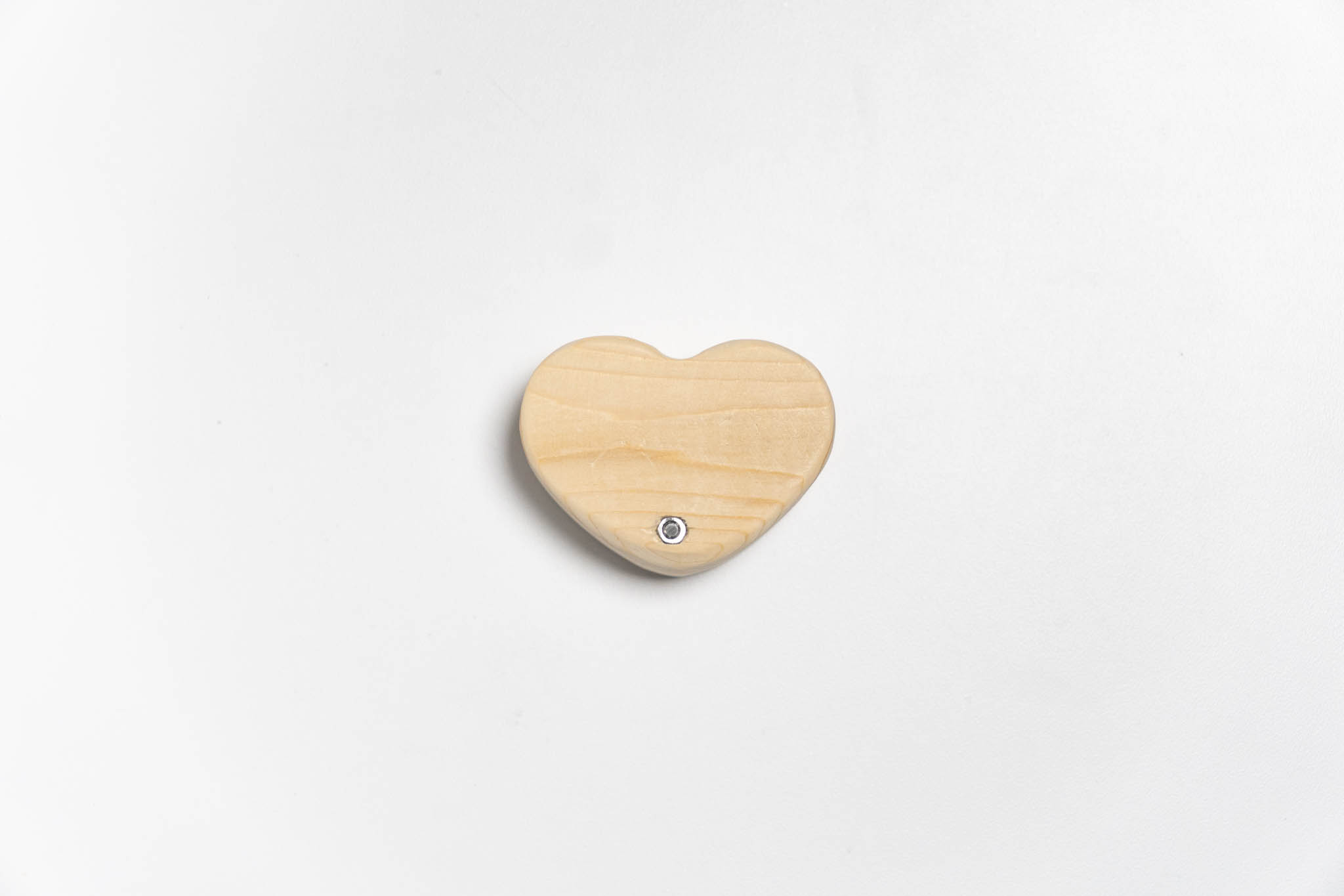 bottom view of a small heart-shaped wooden beige box with its lid ancored around the tip, closed