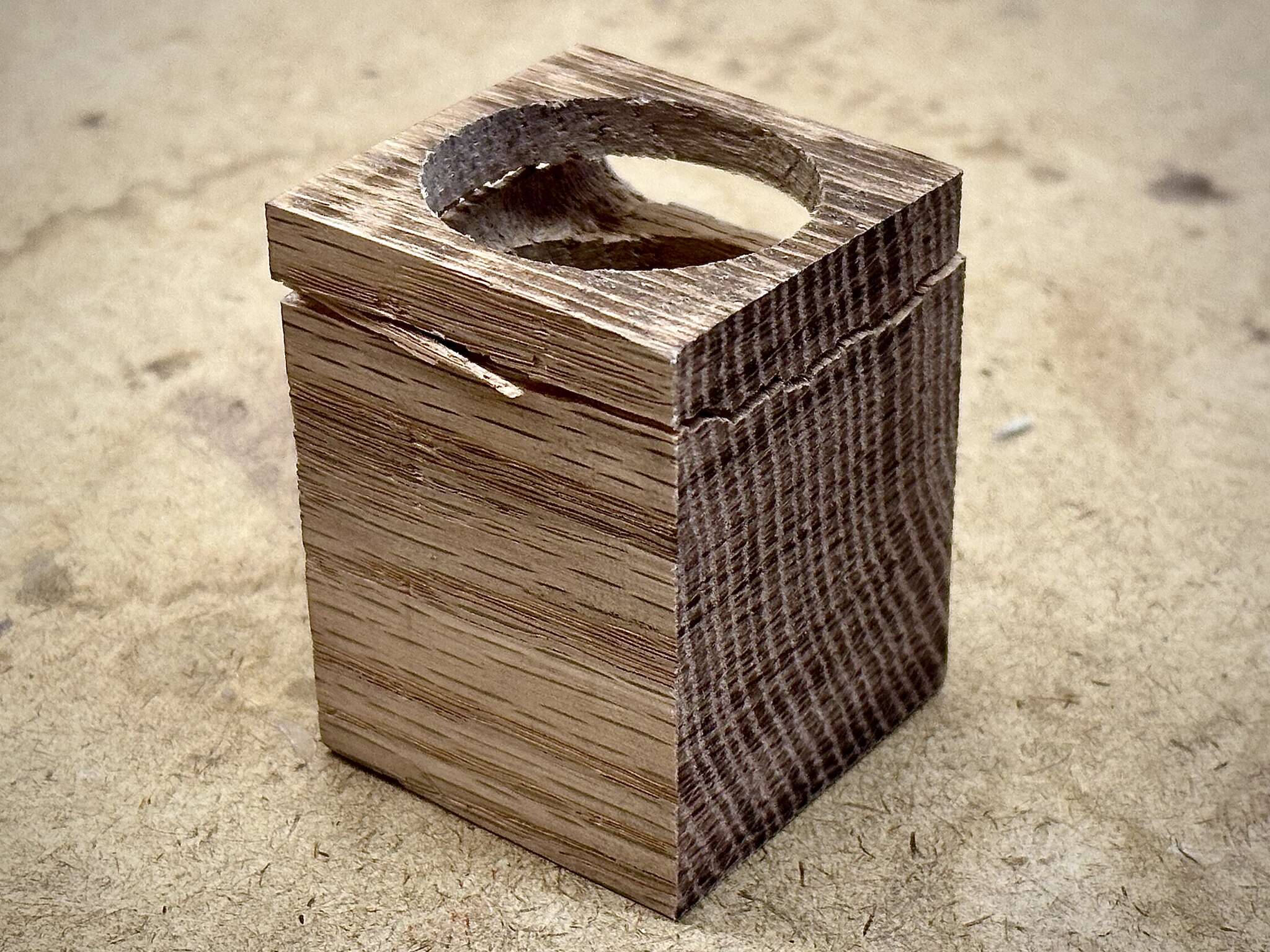 a tall cubic wood piece, with a big cylindrical hole at its center and a opening slot on its side, top section cracked